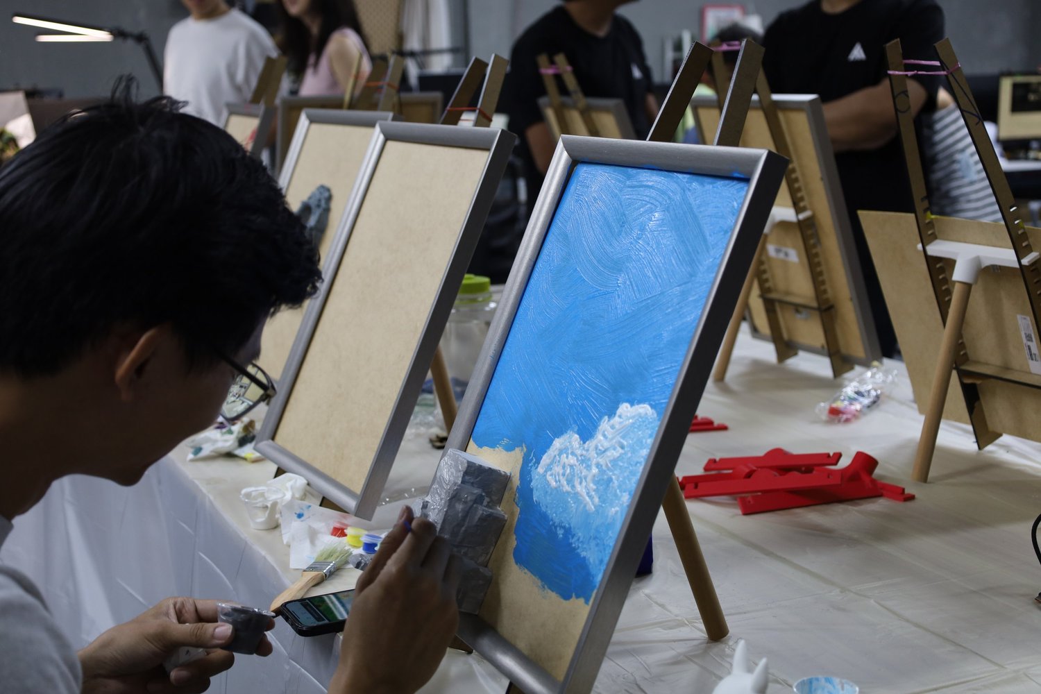 Colleagues painting at easels during a team bonding session in Singapore
