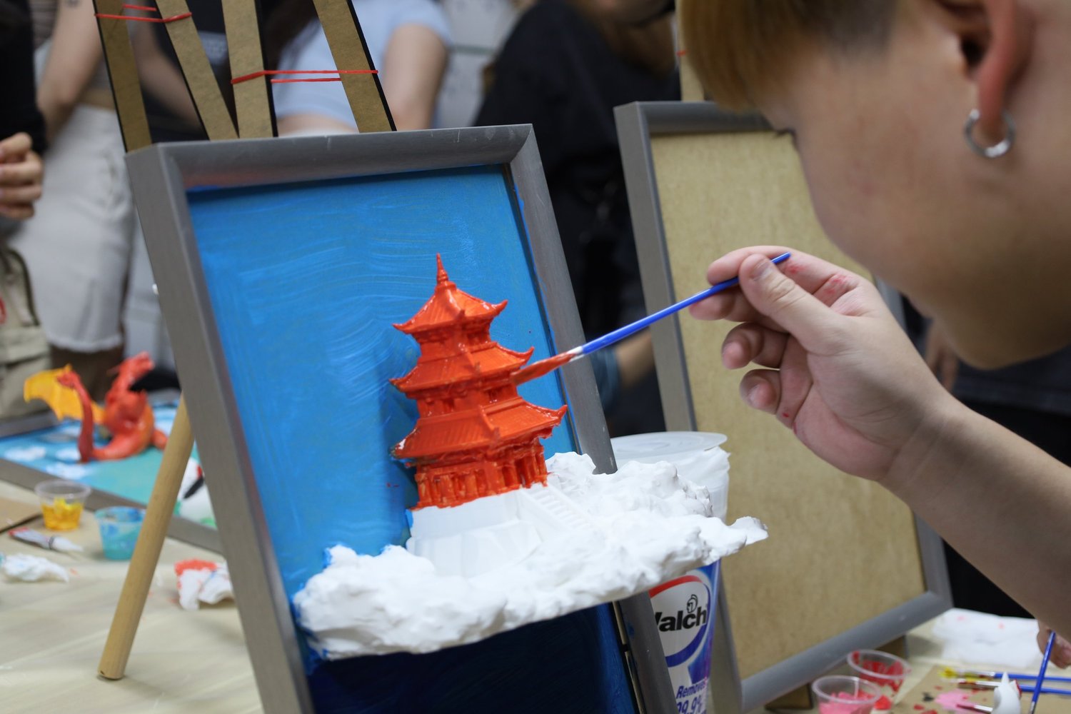 A guest painting a 3D-printed pagoda on canvas during an art jamming date in Singapore